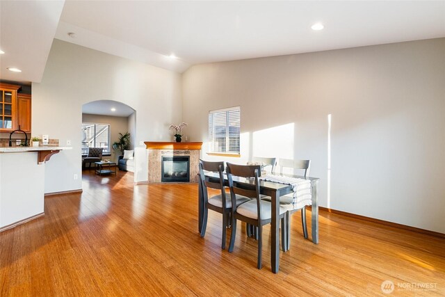 5983 Honeycutt Ct, Ferndale, WA 98248 - dining area with arched walkways, a glass covered fireplace, light wood finished floors, recessed lighting, and high vaulted ceiling
