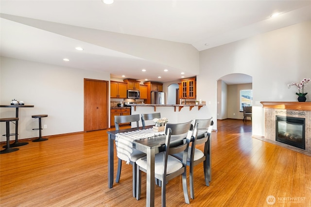 5983 Honeycutt Ct, Ferndale, WA 98248 - dining area with arched walkways, light wood-style floors, vaulted ceiling, recessed lighting, and a premium fireplace