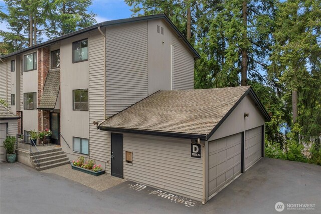 13573 Linden Ave N Unit 302, Seattle, WA 98133 - view of front facade featuring roof with shingles and a detached garage