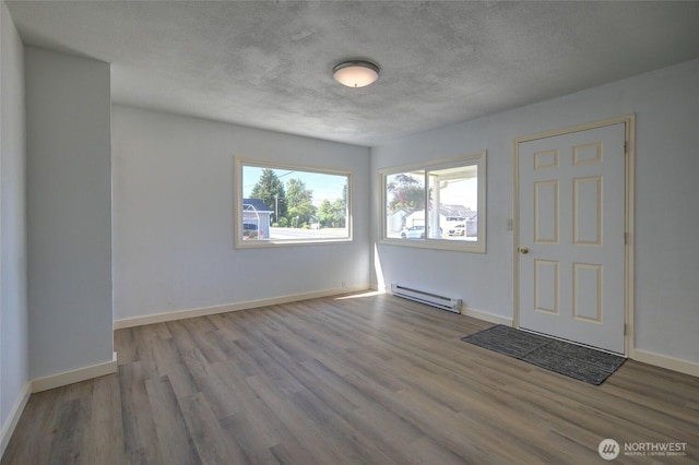 408 N 11th St, Elma, WA 98541 - empty room featuring baseboard heating, wood finished floors, and a textured ceiling