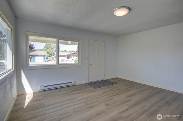 408 N 11th St, Elma, WA 98541 - spare room with baseboard heating, wood finished floors, plenty of natural light, and a textured ceiling