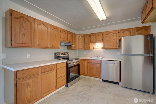 408 N 11th St, Elma, WA 98541 - kitchen with stainless steel appliances, under cabinet range hood, light marble finish floors, light countertops, and brown cabinetry