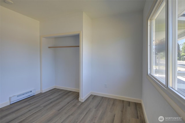 408 N 11th St, Elma, WA 98541 - unfurnished bedroom with a baseboard heating unit, wood finished floors, and a closet