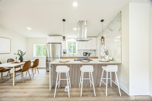 1322 Crescent Ave, Centralia, WA 98531 - kitchen with freestanding refrigerator, island exhaust hood, a peninsula, a breakfast bar, and light wood-style flooring