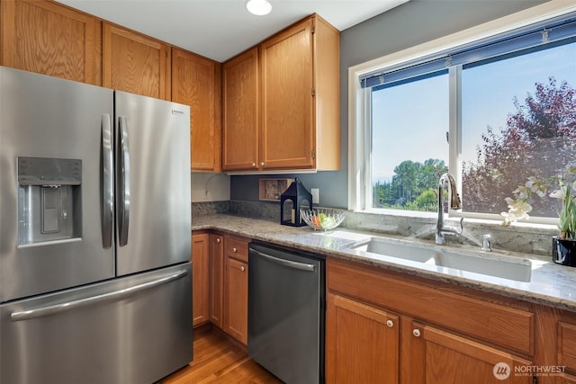 7332 156th St SE, Snohomish, WA 98296 - kitchen with stainless steel appliances, light stone counters, brown cabinetry, and light wood-style floors