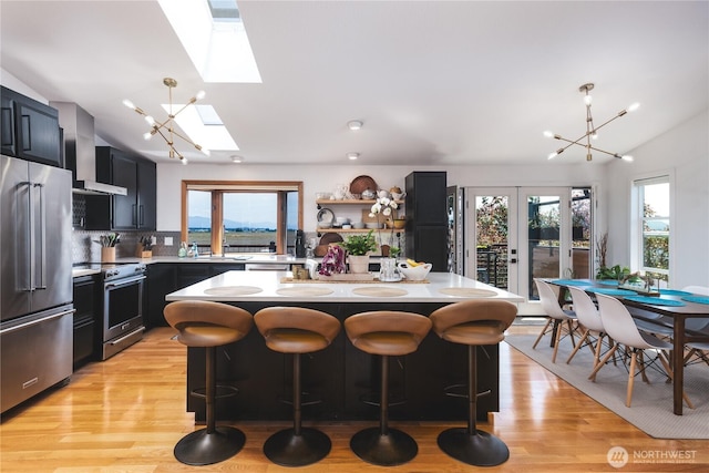 14785 Channel Dr, La Conner, WA 98257 - kitchen with stainless steel appliances, wall chimney exhaust hood, a skylight, vaulted ceiling, and light countertops