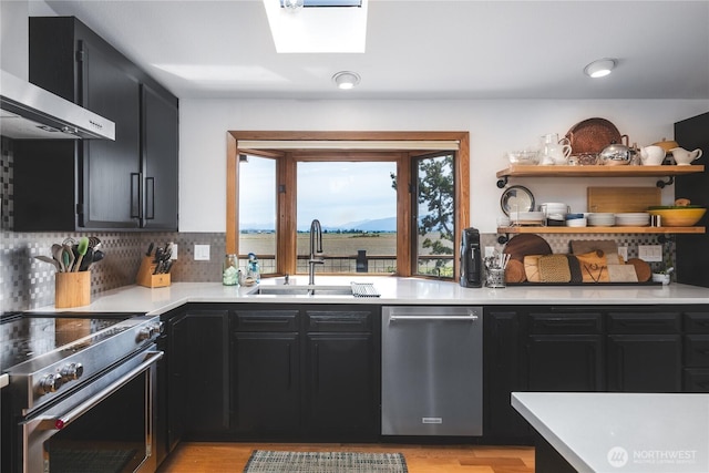 14785 Channel Dr, La Conner, WA 98257 - kitchen with dark cabinetry, exhaust hood, appliances with stainless steel finishes, light countertops, and open shelves
