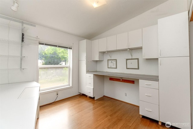 1106 29th St SE, Auburn, WA 98002 - kitchen featuring built in desk, vaulted ceiling, light wood-type flooring, and white cabinetry