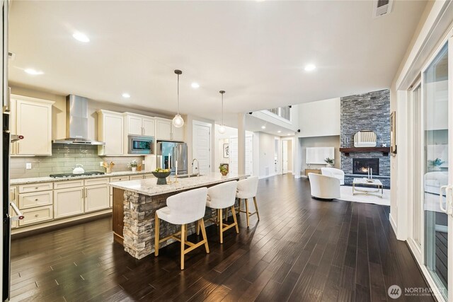 24130 145th Ave SE, Snohomish, WA 98296 - kitchen featuring wall chimney range hood, stainless steel appliances, open floor plan, dark wood-type flooring, and a fireplace