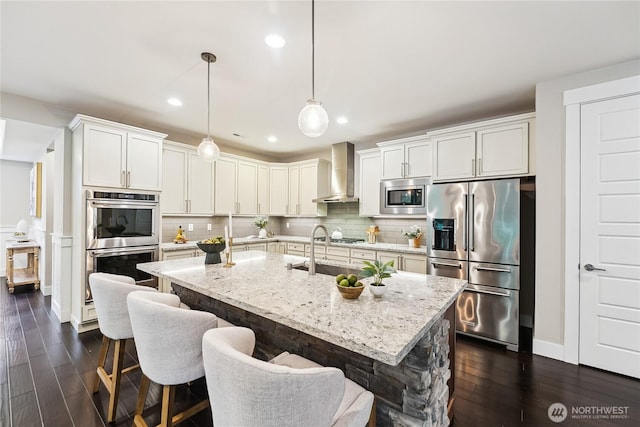 24130 145th Ave SE, Snohomish, WA 98296 - kitchen with stainless steel appliances, wall chimney exhaust hood, dark wood-type flooring, light stone countertops, and a kitchen breakfast bar