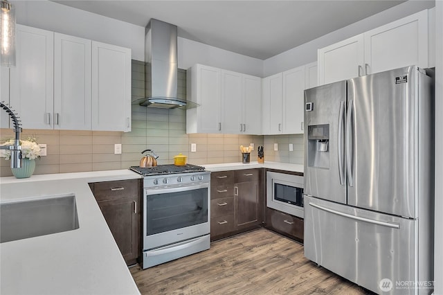 8537 22nd Pl NE, Seattle, WA 98115 - kitchen with stainless steel appliances, wall chimney range hood, light countertops, and dark brown cabinetry