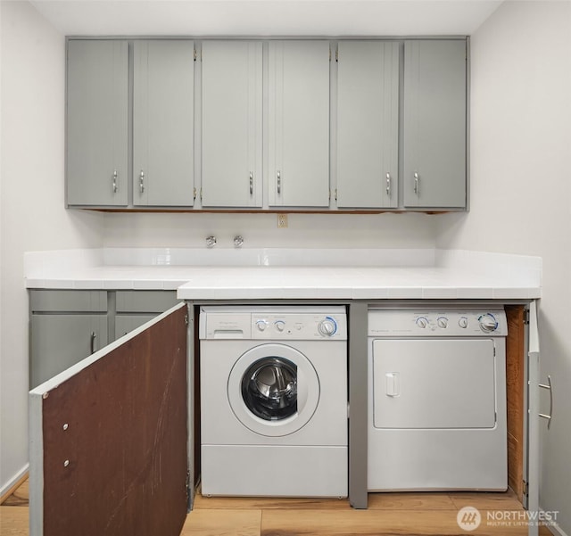 8005 Sand Point Way NE Unit A52, Seattle, WA 98115 - washroom with separate washer and dryer, cabinet space, and light wood-style flooring
