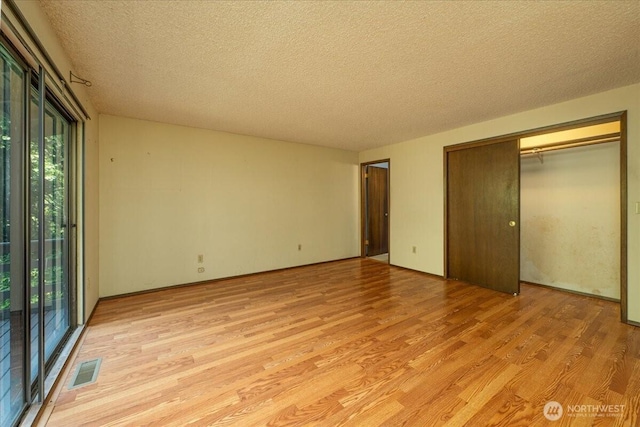 18707 25th Ave NE, Lake Forest Park, WA 98155 - unfurnished bedroom featuring light wood-style floors, a textured ceiling, and a closet