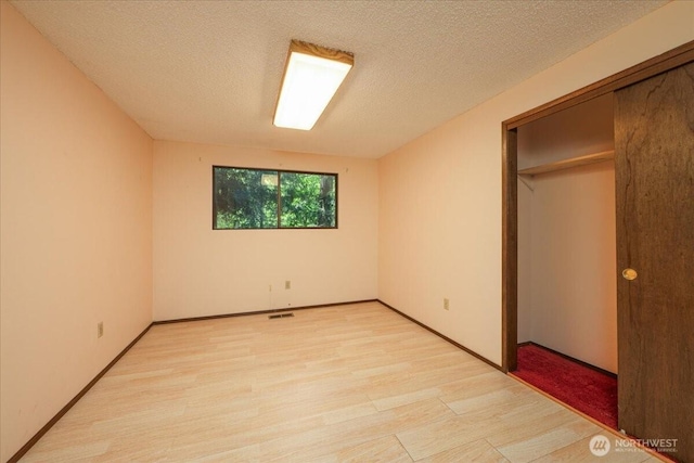 18707 25th Ave NE, Lake Forest Park, WA 98155 - unfurnished bedroom featuring light wood-style floors, a closet, and a textured ceiling