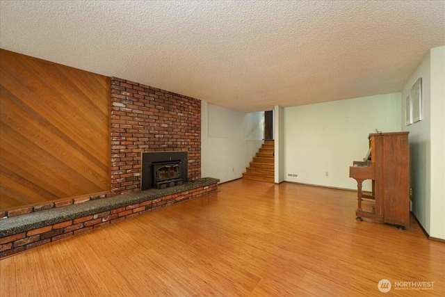18707 25th Ave NE, Lake Forest Park, WA 98155 - unfurnished living room featuring wood finished floors, stairway, a textured ceiling, a brick fireplace, and wooden walls