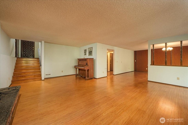 18707 25th Ave NE, Lake Forest Park, WA 98155 - unfurnished living room featuring wood finished floors, stairway, a chandelier, and a textured ceiling