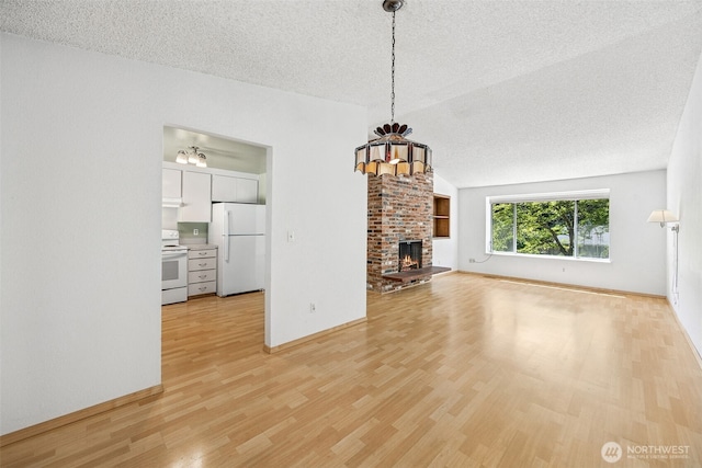2810 Brentwood Dr SE, Lacey, WA 98503 - unfurnished living room with light wood-style floors, a chandelier, a textured ceiling, a fireplace, and vaulted ceiling