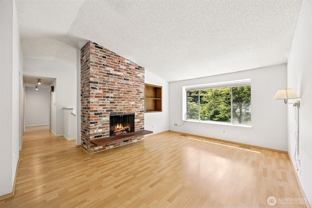 2810 Brentwood Dr SE, Lacey, WA 98503 - unfurnished living room with lofted ceiling, a textured ceiling, wood finished floors, and a brick fireplace