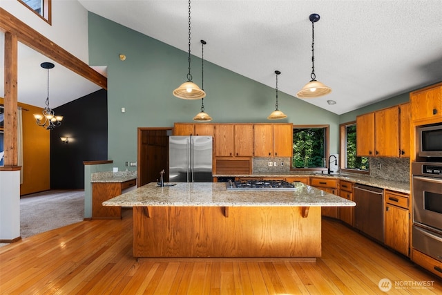 2515 87th Avenue Ct E, Edgewood, WA 98371 - kitchen featuring appliances with stainless steel finishes, high vaulted ceiling, brown cabinetry, backsplash, and a kitchen island