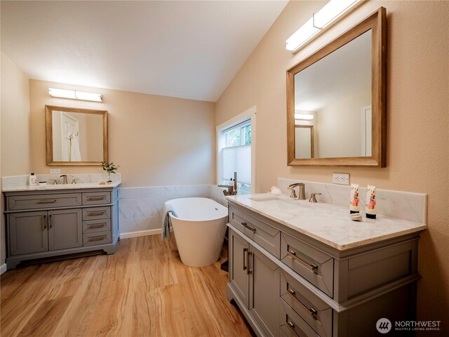 4805 Cushman Rd NE Unit 115, Olympia, WA 98506 - bathroom with wood finished floors, two vanities, a freestanding bath, and vaulted ceiling