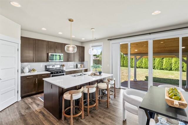 605 26th Avenue Ct, Milton, WA 98354 - kitchen with stainless steel appliances, dark brown cabinets, a kitchen breakfast bar, tasteful backsplash, and light countertops