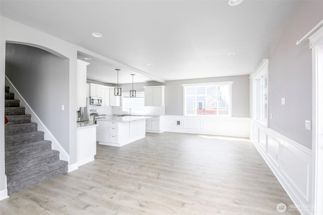 7830 A St, Tacoma, WA 98408 - unfurnished living room with light wood-style floors, recessed lighting, stairs, arched walkways, and a wainscoted wall