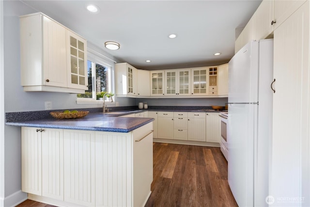 1418 W Mukilteo Blvd, Everett, WA 98203 - kitchen with white appliances, a peninsula, dark countertops, dark wood finished floors, and glass insert cabinets