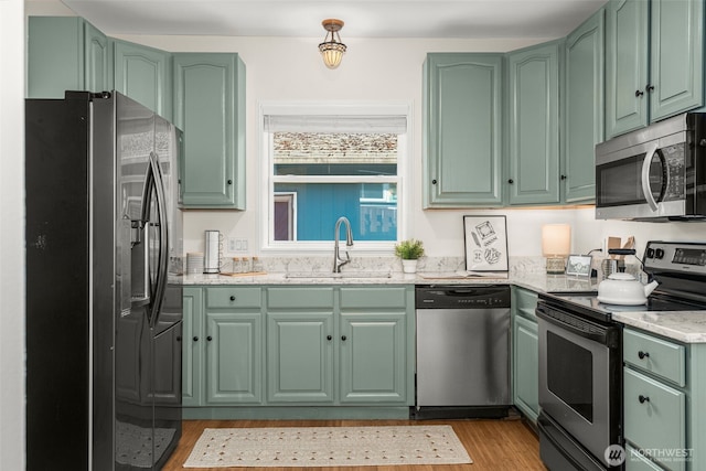 4506 46th Ave SW, Seattle, WA 98116 - kitchen with appliances with stainless steel finishes, green cabinetry, light wood-type flooring, and light stone countertops