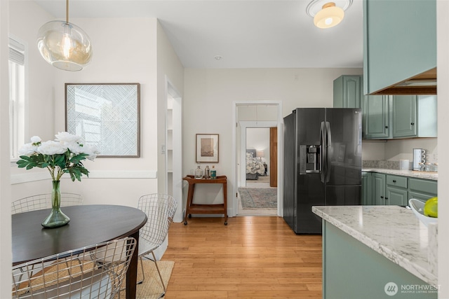 4506 46th Ave SW, Seattle, WA 98116 - kitchen with refrigerator with ice dispenser, green cabinetry, light wood finished floors, light stone countertops, and hanging light fixtures