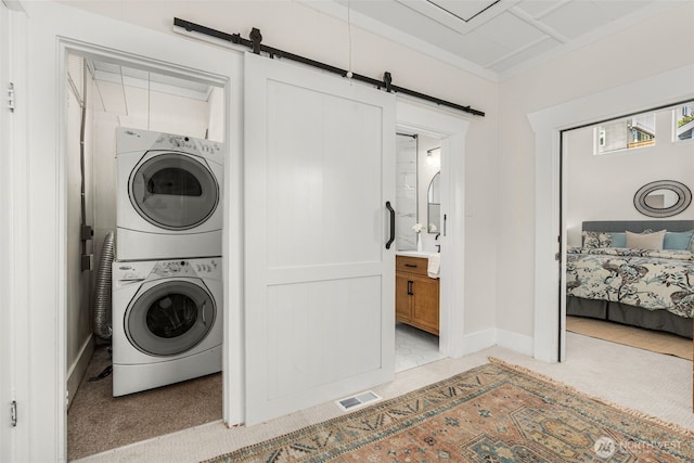 4506 46th Ave SW, Seattle, WA 98116 - washroom with estacked washer and dryer, a barn door, and light carpet