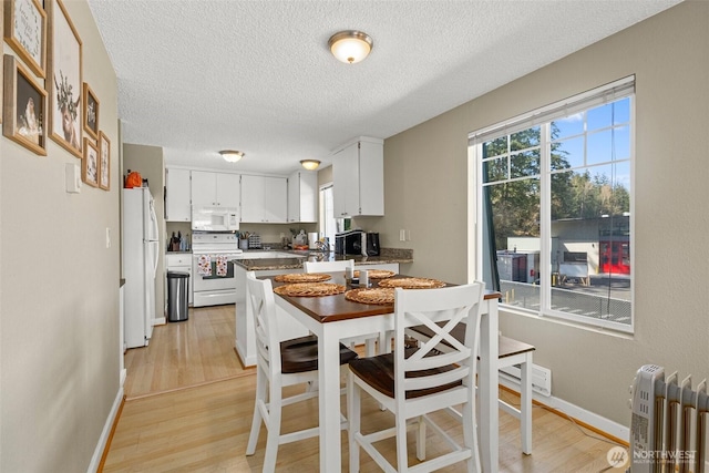 3302 W Tapps Dr E, Lake Tapps, WA 98391 - kitchen featuring white appliances, radiator heating unit, light wood-style flooring, a textured ceiling, and white cabinets