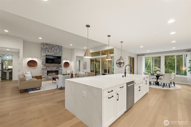 332 138th Pl SE, Auburn, WA 98092 - kitchen with a stone fireplace, light wood-type flooring, open floor plan, white cabinetry, and light stone countertops
