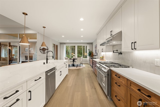332 138th Pl SE, Auburn, WA 98092 - kitchen with stainless steel appliances, light wood-style floors, under cabinet range hood, light stone counters, and white cabinetry