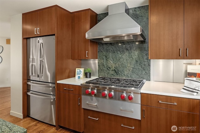 19081 11th Ave NW, Shoreline, WA 98177 - kitchen featuring appliances with stainless steel finishes, wall chimney range hood, light wood-style floors, backsplash, and brown cabinetry