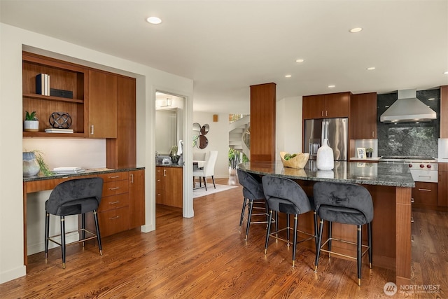 19081 11th Ave NW, Shoreline, WA 98177 - kitchen featuring wall chimney range hood, stainless steel refrigerator with ice dispenser, dark wood-style flooring, a breakfast bar area, and built in desk