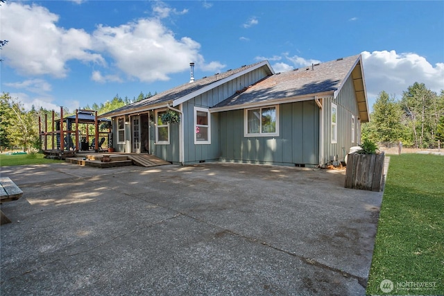 12310 Morris Rd SE, Yelm, WA 98597 - back of house featuring board and batten siding, a shingled roof, a wooden deck, and a patio