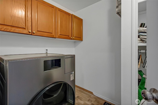 12310 Morris Rd SE, Yelm, WA 98597 - washroom featuring washer / clothes dryer, light wood-style floors, and cabinet space
