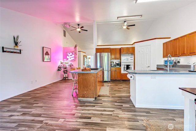 12310 Morris Rd SE, Yelm, WA 98597 - kitchen with freestanding refrigerator, ceiling fan, high vaulted ceiling, brown cabinetry, and a kitchen breakfast bar
