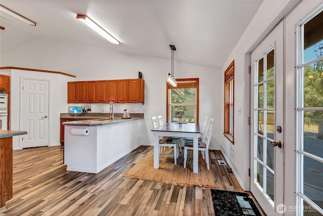 12310 Morris Rd SE, Yelm, WA 98597 - kitchen with lofted ceiling, brown cabinets, a peninsula, light wood-type flooring, and pendant lighting