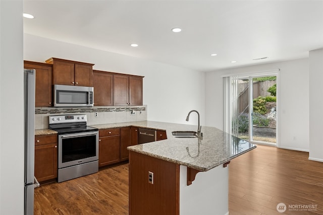 7022 Raptor Ave NE, Lacey, WA 98516 - kitchen with appliances with stainless steel finishes, a peninsula, dark wood-style flooring, a breakfast bar area, and recessed lighting