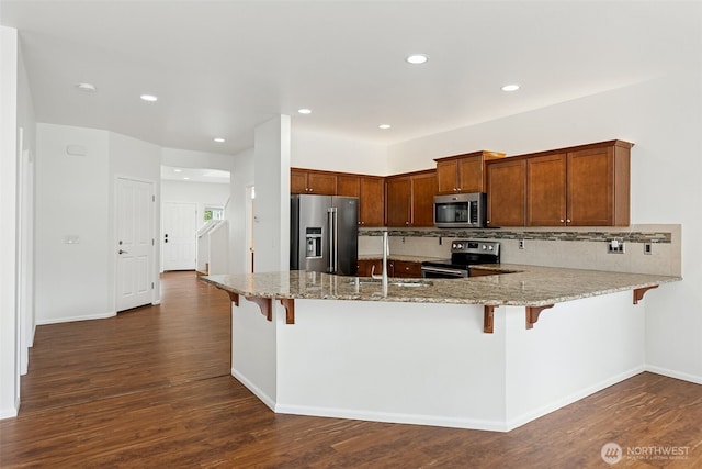 7022 Raptor Ave NE, Lacey, WA 98516 - kitchen with stainless steel appliances, a peninsula, light stone countertops, tasteful backsplash, and dark wood-style floors