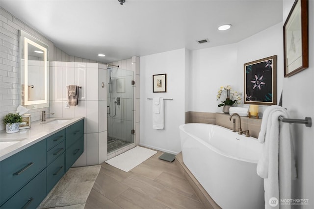 177 107th Ave NE Unit 1906, Bellevue, WA 98004 - bathroom featuring a freestanding bath, a stall shower, double vanity, recessed lighting, and tasteful backsplash