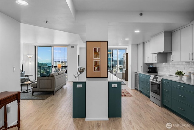 177 107th Ave NE Unit 1906, Bellevue, WA 98004 - kitchen featuring electric range, backsplash, light wood finished floors, wall chimney exhaust hood, and open floor plan