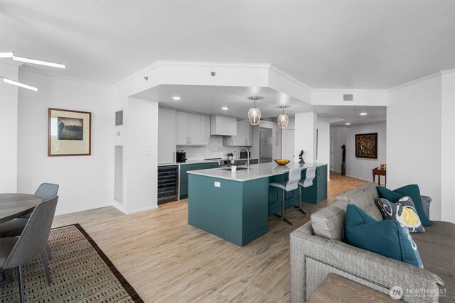 177 107th Ave NE Unit 1906, Bellevue, WA 98004 - kitchen featuring light countertops, a breakfast bar area, light wood-type flooring, open floor plan, and ornamental molding