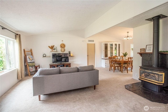 1729 154th St S, Spanaway, WA 98387 - living area featuring a wood stove, lofted ceiling, light carpet, a chandelier, and a textured ceiling