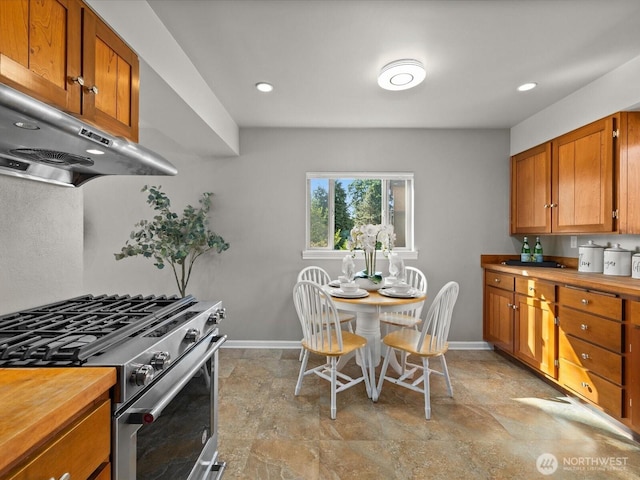 13514 3rd Ave NE, Seattle, WA 98125 - kitchen with stainless steel gas range, under cabinet range hood, brown cabinets, light stone finish floors, and butcher block counters
