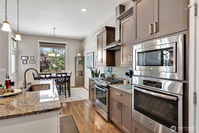 9511 W Floyd Dr, Cheney, WA 99004 - kitchen with stainless steel appliances, light wood finished floors, tasteful backsplash, light stone counters, and pendant lighting