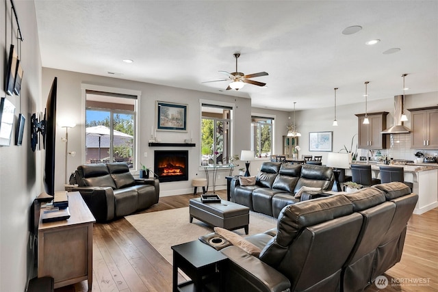 9511 W Floyd Dr, Cheney, WA 99004 - living area with plenty of natural light, a ceiling fan, a warm lit fireplace, light wood finished floors, and recessed lighting