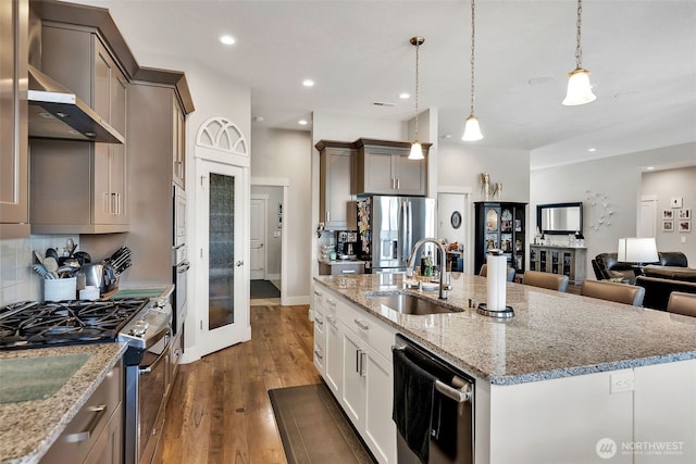 9511 W Floyd Dr, Cheney, WA 99004 - kitchen with stainless steel appliances, decorative backsplash, an island with sink, dark wood-type flooring, and light stone counters