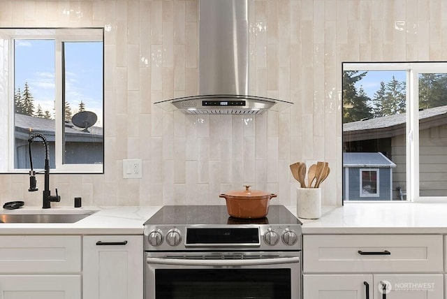 2500 S 370th Unit 227, Federal Way, WA 98003 - kitchen with stainless steel electric range, wall chimney range hood, decorative backsplash, white cabinetry, and healthy amount of natural light
